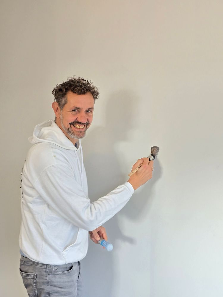 Roland Visser werkt een wand bij met een kwast